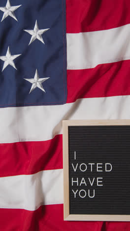 Vertical-Video-Of-Sign-Reading-I-Voted-Have-You-Lying-On-US-Stars-And-Stripes-Flag-For-American-Election-2024